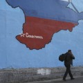 A man passes a mural showing a map of Crimea in Russian national colours on a street in Moscow