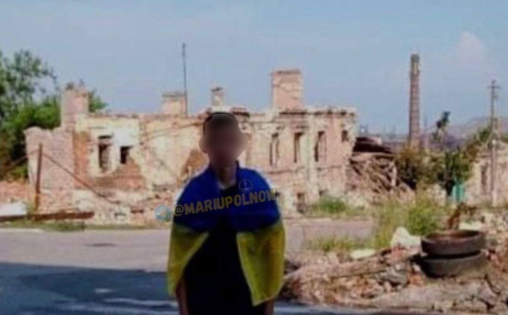 У Маріуполі юнак сфотографувався біля розбомбленого будинку з прапором України